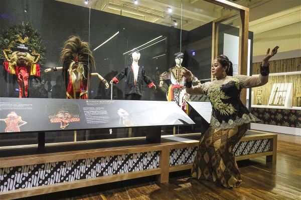 印尼籍新住民林采妮（右）出借她的孔雀羽冠虎面獅舞劇兒童版劇服，供臺博館展出。（林格立攝）