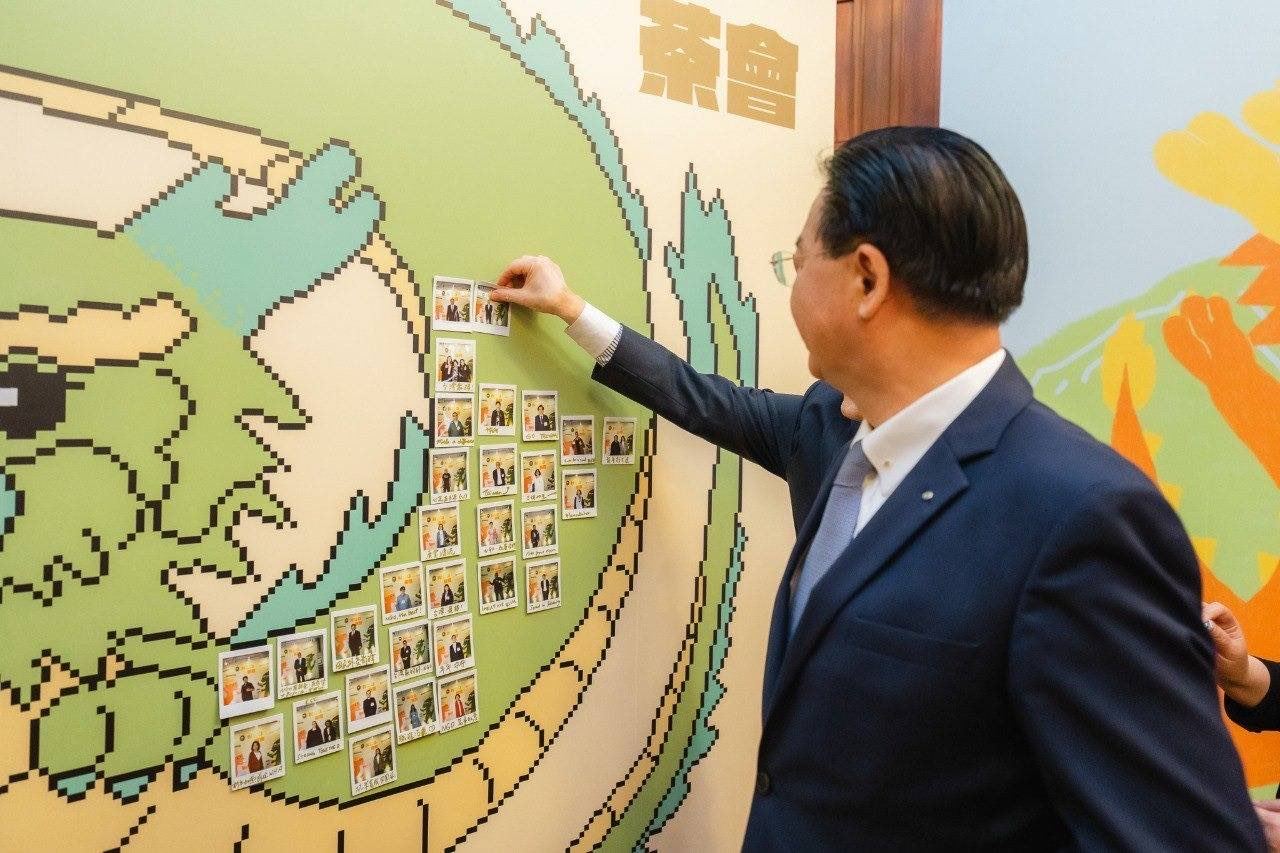 外交部長吳釗燮在象徵公私協力的連儂牆面張貼拍立得相片。