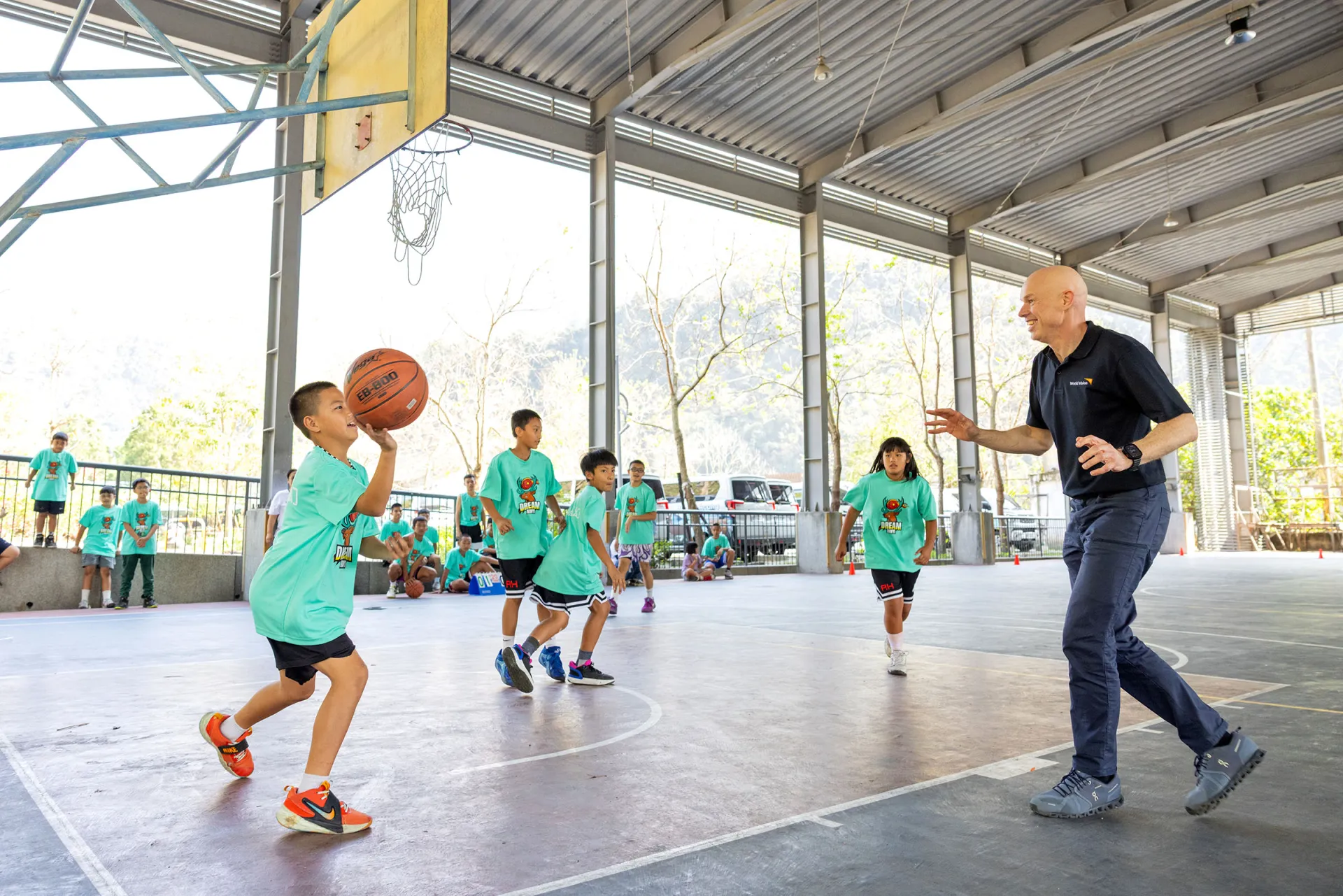 安德魯‧莫利在地利村風雨球場，和信義夢幻隊的孩子報隊打籃球。(台灣世界展望會提供)