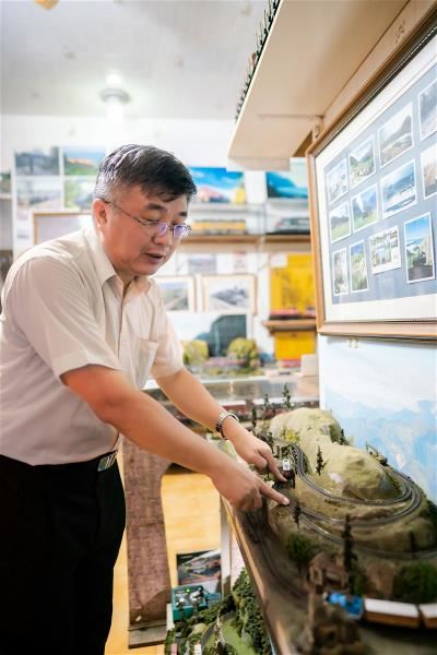 一生情繫阿里山鐵路的蘇昭旭,正興致盎然地以模型解釋阿里山鐵路「之字形」工法。