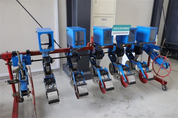 This towed dry-field seed sowing machine—which simultaneously prepares the ground, plows furrows, sows seeds, and covers them with soil—is a labor-saving device employed in growing soybeans.