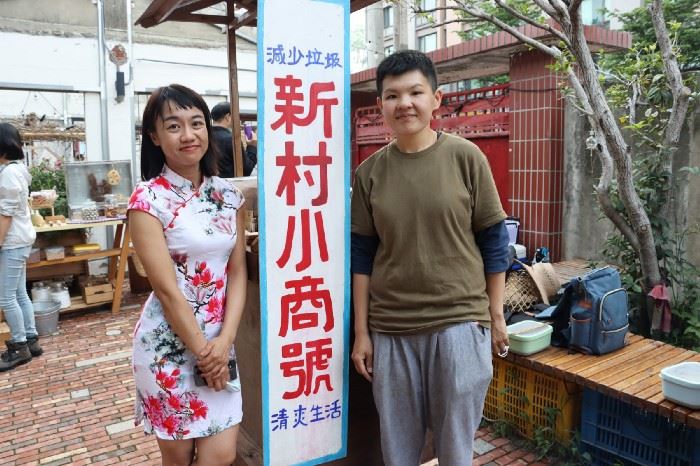 新村小商號創辦人鳳嬌（左）與拉拉（右）與市集攤位招牌合影。攝影／蔡昀彤