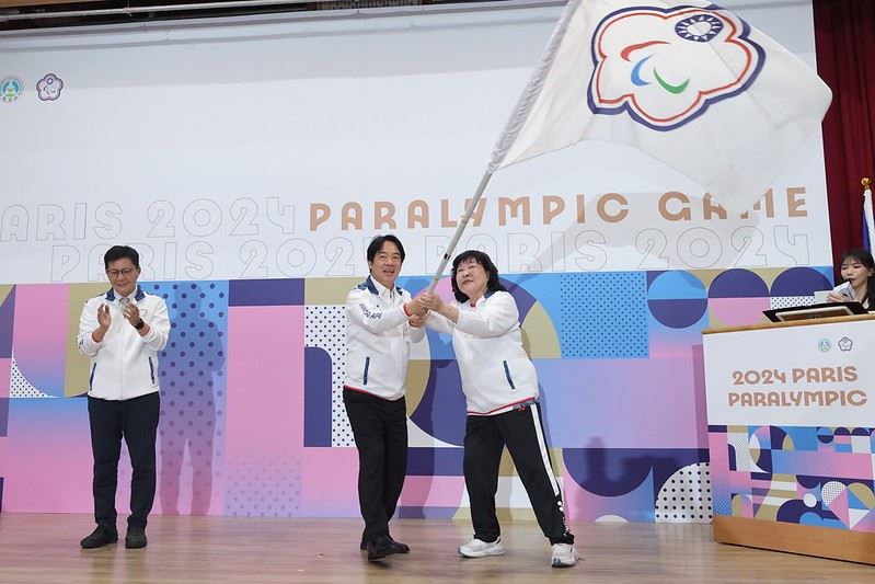 President Lai Ching-te (center) waves Team Taiwan’s Paralympic flag with Mu Ming-chu, president of the Chinese Taipei Paralympic Committee and head of the country’s Paralympic delegation, during a ceremony at the Sports Administration Aug. 23 in Taipei City. (Courtesy of Presidential Office)