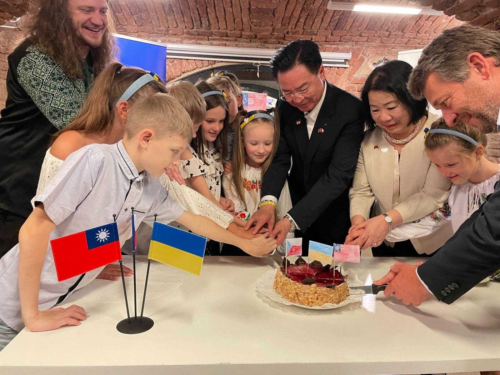 Foreign Minister Joseph Wu cuts a cake with Ukrainian children in the People in Need headquarters on Wednesday in Prague.
