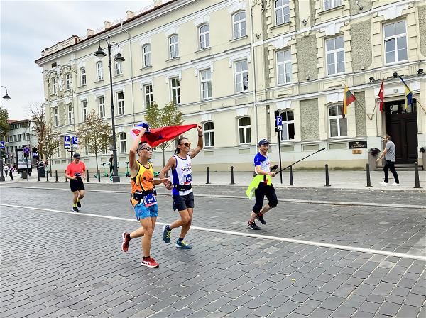 洪國展（左2）最終以4小時30分的成績，與陪跑員齊跨越立陶宛馬拉松終點線。（楊鍾鼎提供）