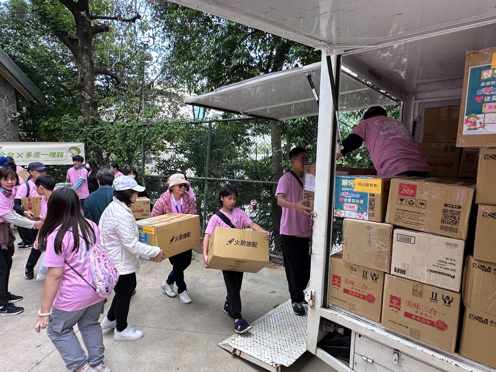 眾人齊力將聖誕禮物搬上車，以車隊方式傳遞關懷與祝福。(芥菜種會提供)