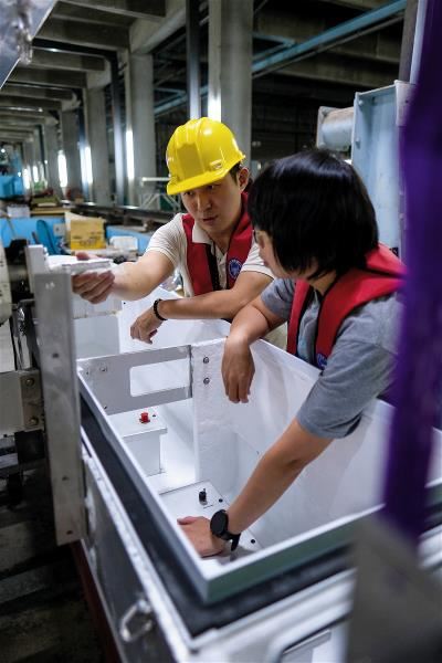 Chen Szu-ying and the team’s systems engineer install a battery pack in a trash skimmer.
