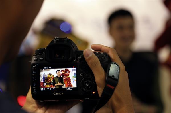 越南籍網紅主持人Quang Vinh，對著鏡頭介紹全亞洲唯一的機器人觀光工廠，他的背後是一隻舞獅機器人。 